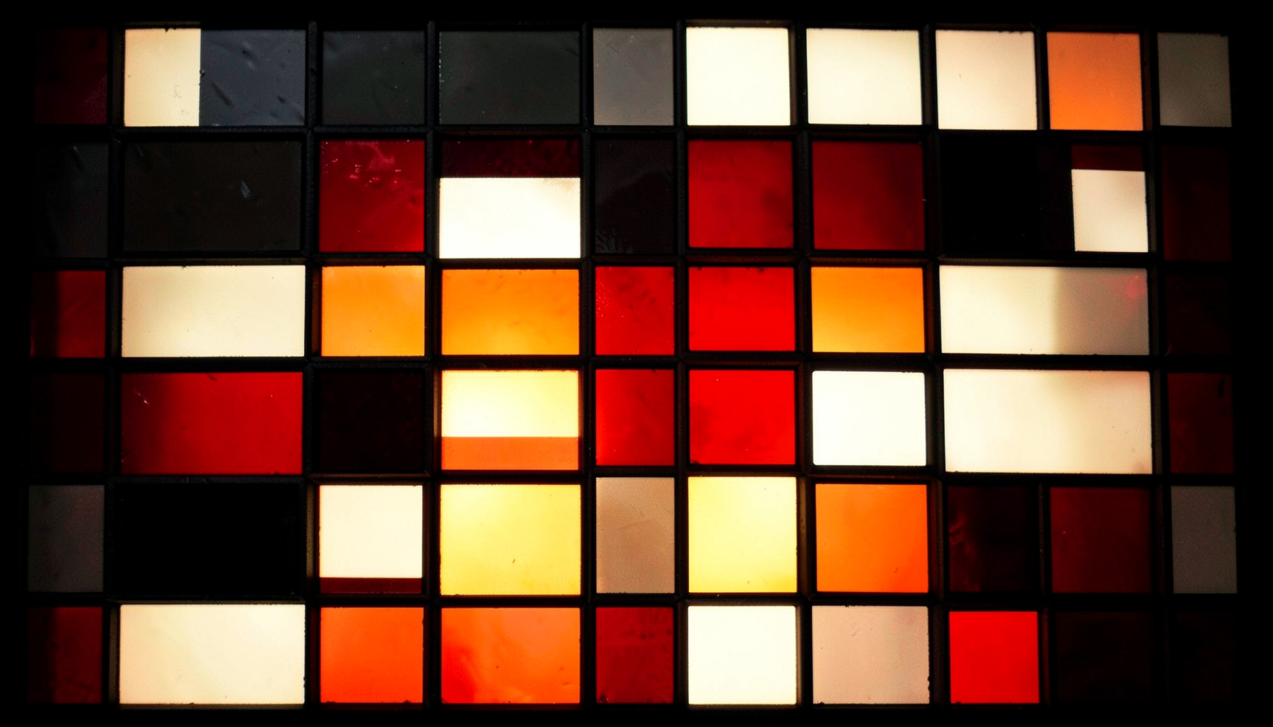 A stained-glass composition with bold leaded segments in charcoal black, ivory white, and crimson red, forming a dramatic chessboard-inspired geometric pattern